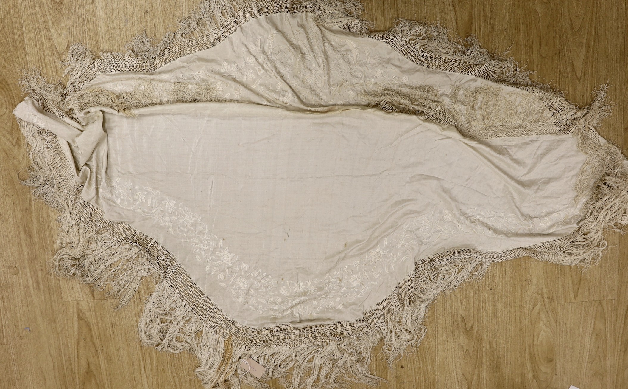 A late 19th/early 20th century Chinese cream silk shawl with cream silk embroidery and fringing, converted to a ladies cape